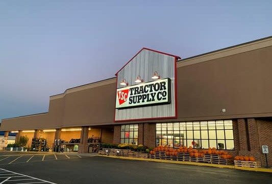 Front of Tractor Supply Co. with orange pumpkins and yellow flowers on display