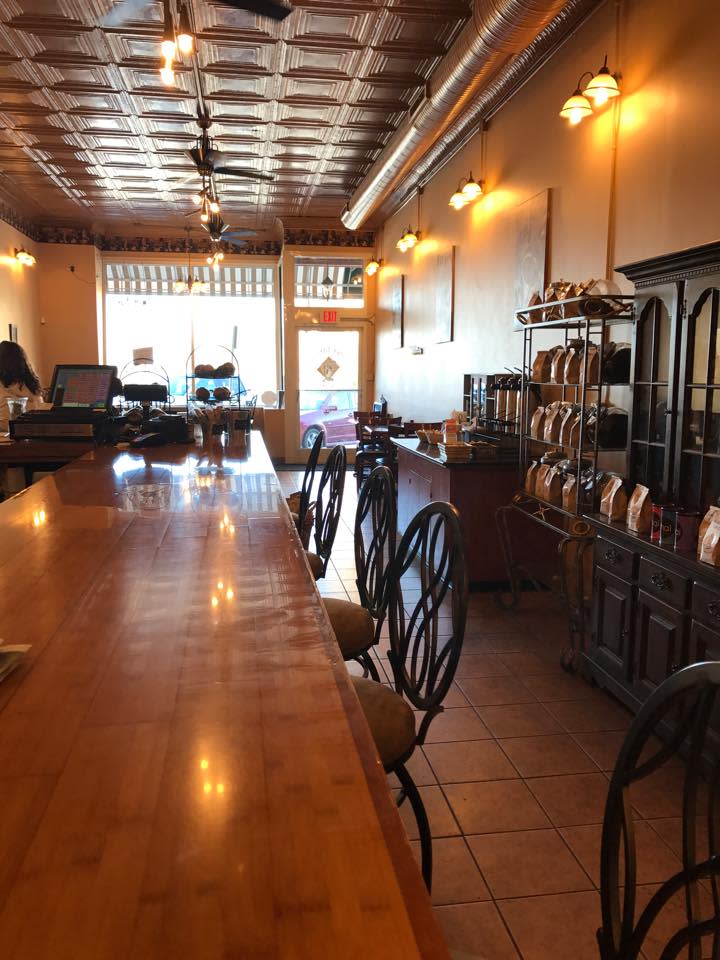 A coffee shop with a long wooden counter with chairs pulled up