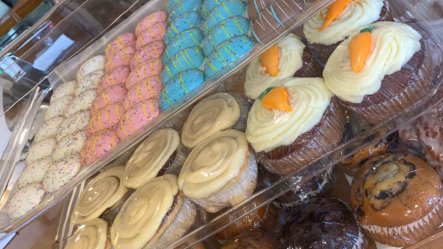 A bakery display case with colorful cookies, cupcakes, and muffins