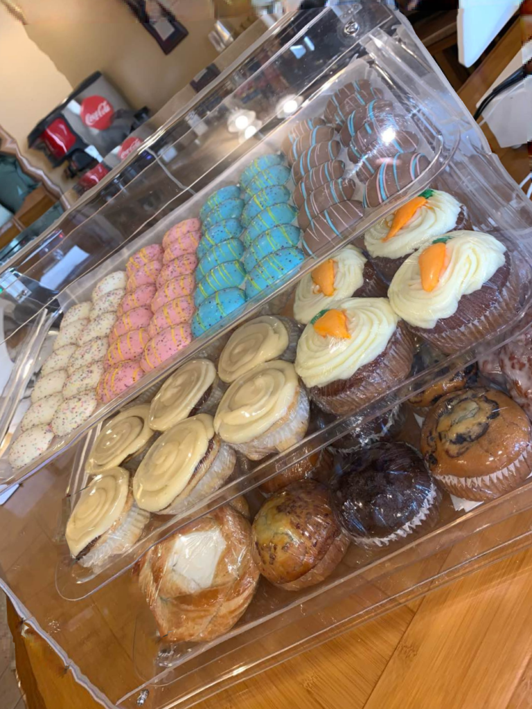 A bakery display case with colorful cookies, cupcakes, and muffins