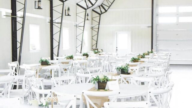 A white indoors event space with white tables and chairs