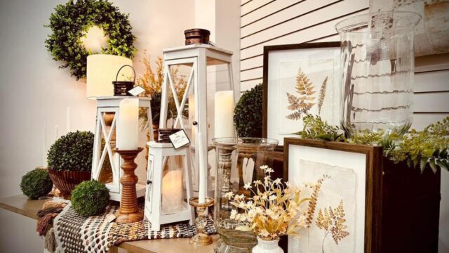 A table display of home decor items including candles, prints and greenery