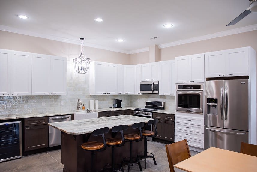 A kitchen with white upper cabinets, a gray stone countertop and dark lower cabinets