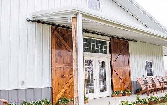 Glass-paned double doors flanked by wooden barn doors on a white barn