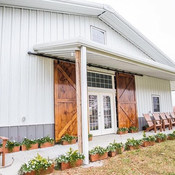 Glass-paned double doors flanked by wooden barn doors on a white barn